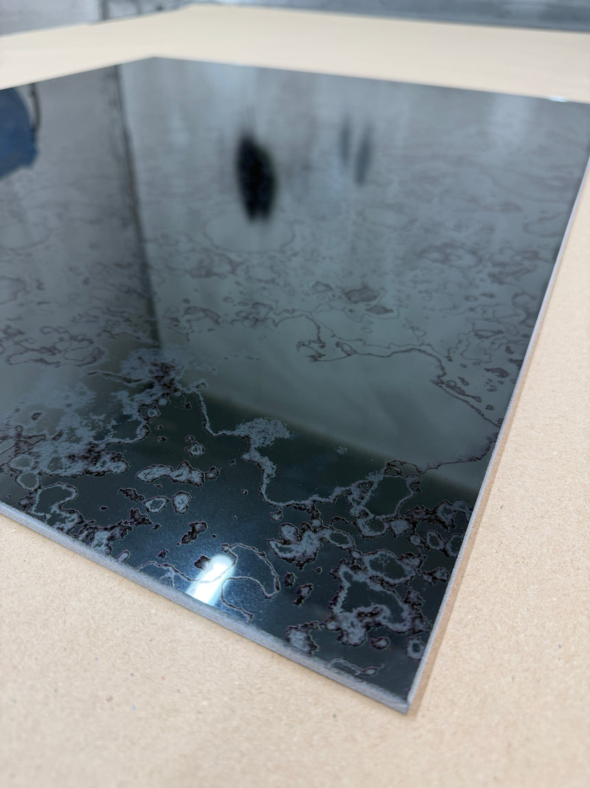 A close up of a grey antique mirror splashback on a light background showing a rusted pattern
