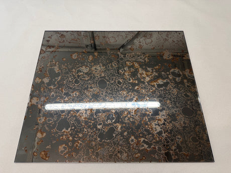 A square bronze antique mirror splashback showing a reflection sat on a white background