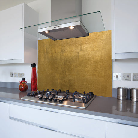 A kitchen splashback featuring a printed glass panel with an Egyptian gold design, installed above the stove and countertop.