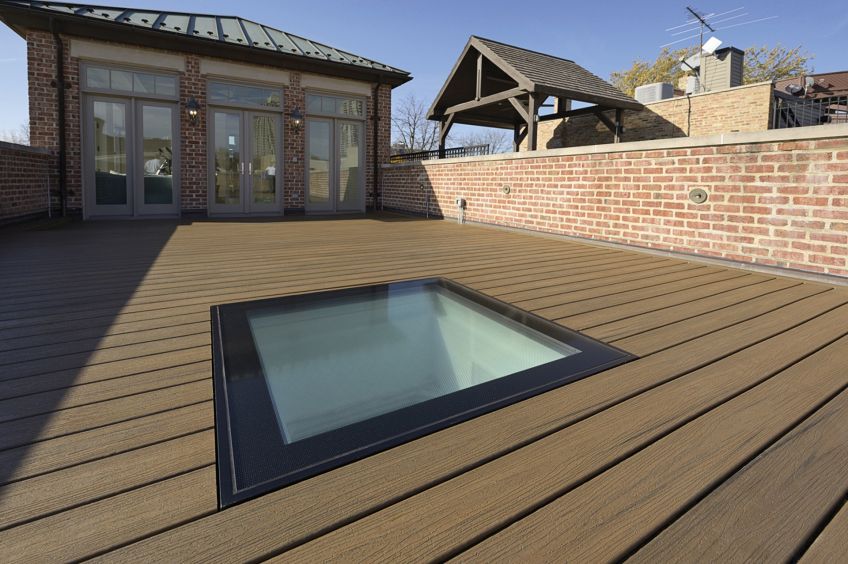 walk on glass skylight on a wooden deck with a brick building in the background